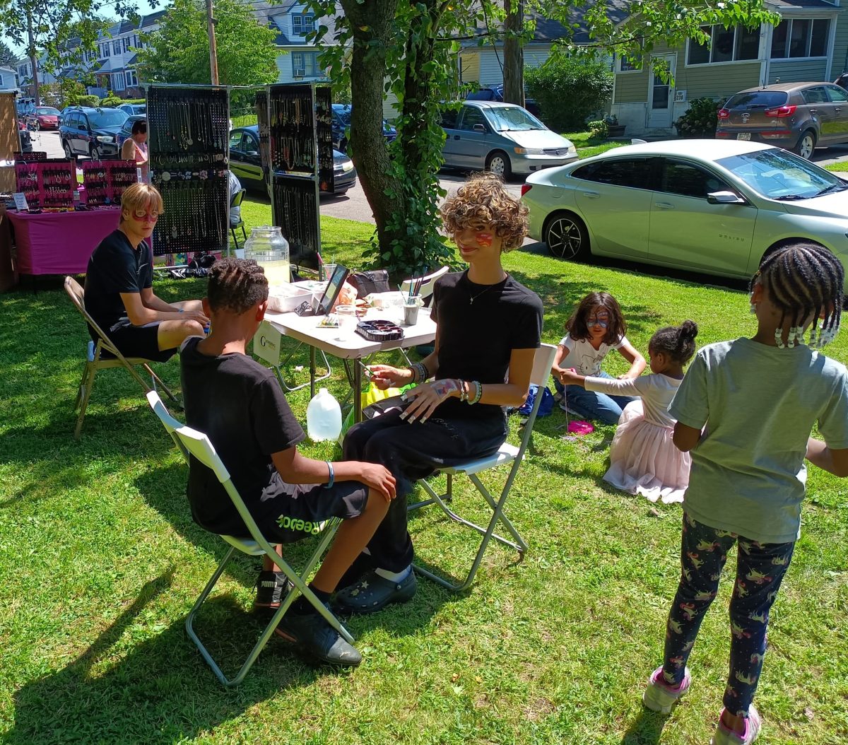 Gathering Delco youth offering face painting at a community event, all with colorfully painted faces themselves.